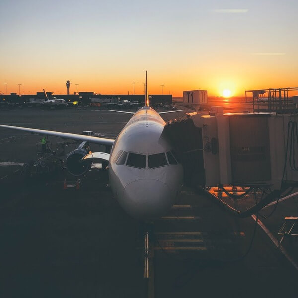 White commercial jet parked at airport gate under an evening sky.