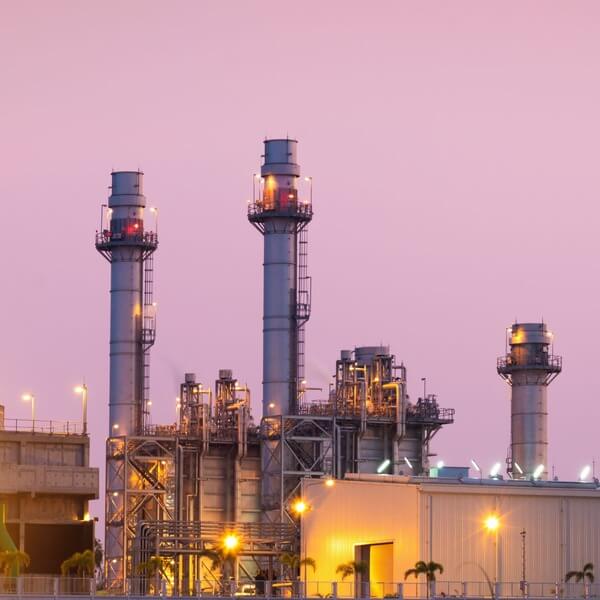 Power plant with tall chimneys and industrial structures at sunset.