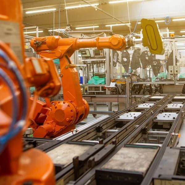 Orange robotic arm operating on an automated assembly line.